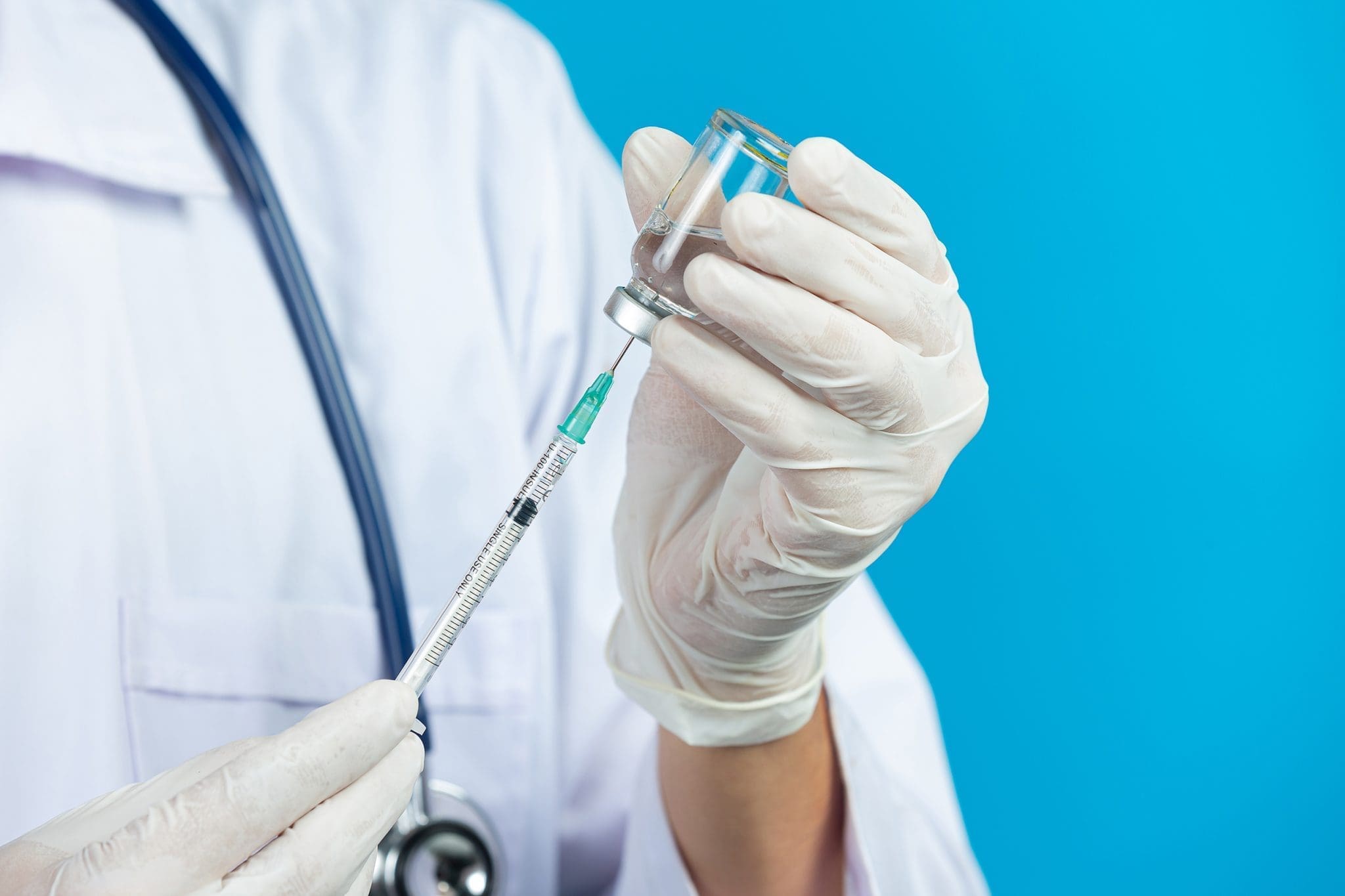 close up picture of doctor's hands holding hypodermic syringe